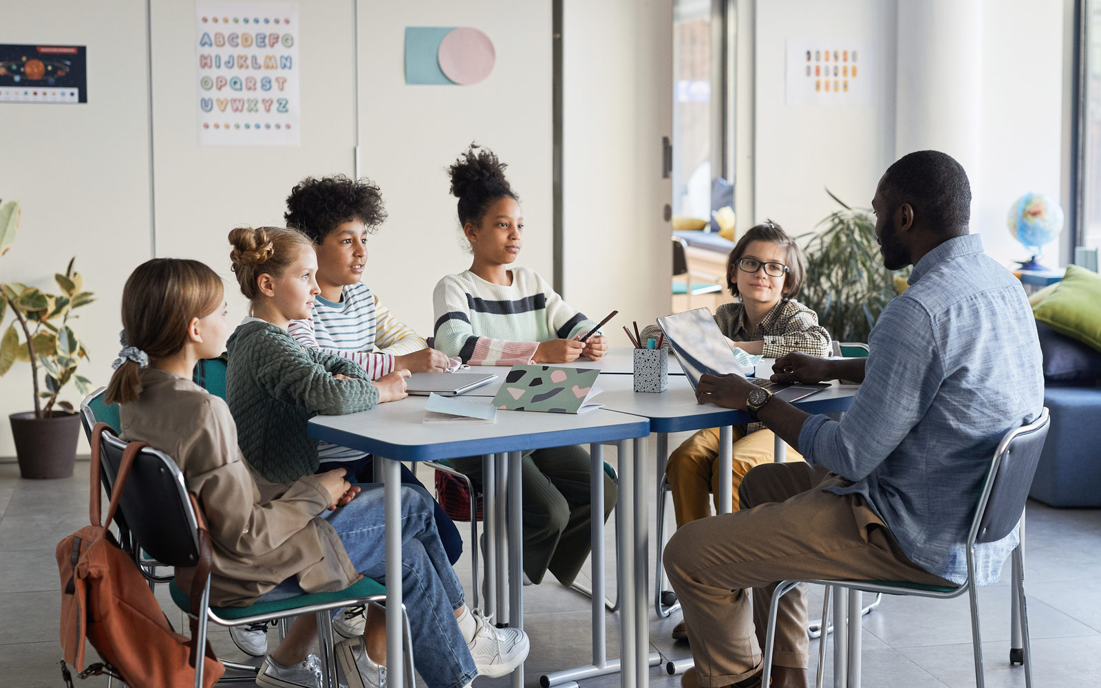Young students and teacher sitting around a table